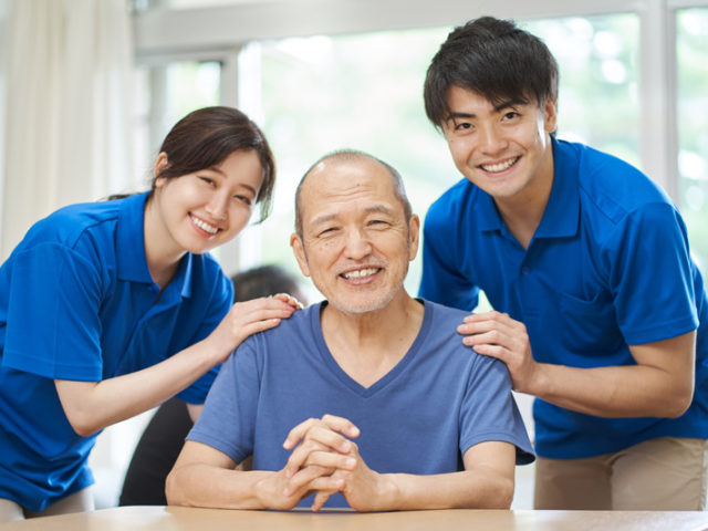 A smiling elderly person and a supporting caregiver