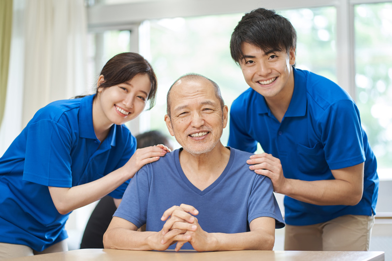 A smiling elderly person and a supporting caregiver
